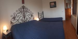 ein Schlafzimmer mit einem blauen Bett mit einem Kopfteil aus Metall in der Unterkunft Casabella Sabaudia in Sabaudia