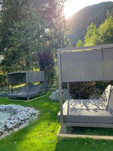 two benches sitting in the grass in a yard at Hotel Burgfrieden in Gais