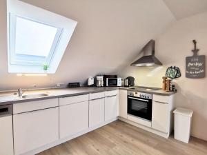a kitchen with white cabinets and a sink and a window at Scholz-Riewerts - gemütliches Apartment mit Küche für 2 Personen in Silberstedt