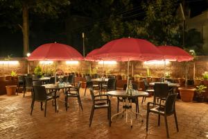 a restaurant with tables and chairs with red umbrellas at Jivanta Mahabaleshwar in Mahabaleshwar