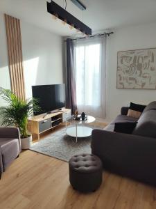 a living room with a couch and a tv at Super appart Tram T2 Paris Déf Arena in Bezons