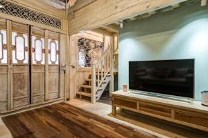 a living room with a large television and a staircase at Tuo Tuo Guest House in Lijiang