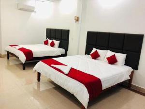 Duas camas com almofadas vermelhas num quarto em EZ Guesthouse em Phnom Penh