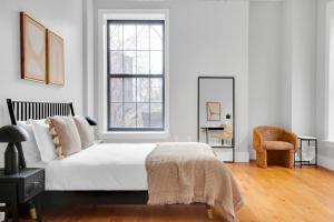 1 dormitorio blanco con 1 cama y 1 silla en Jersey City 2BR w WD DM free shuttle to PATH NYC-761, en Hoboken