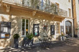 ein Gebäude mit Tischen und Stühlen und einem Balkon in der Unterkunft Olivier Leflaive Hôtel Restaurants in Puligny-Montrachet