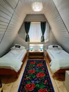 an attic bedroom with two beds and a rug at Casa Ele in Frăsinet