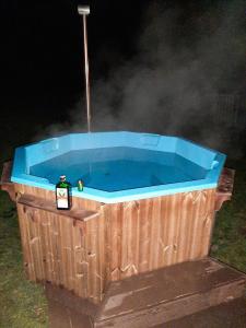 a wooden hot tub with a bottle in it at Casa Ele in Frăsinet