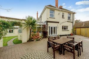 un patio con mesa y bancos frente a una casa en Foy House, en Folkestone