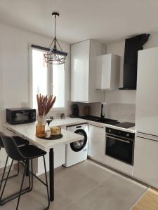 - une cuisine avec des placards blancs et une table avec un lave-vaisselle dans l'établissement Superbe appartement proche la défense et Paris, à Bezons