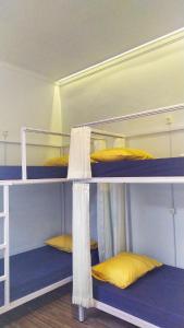 three bunk beds in a room with yellow pillows at ROOM Ijen Dormitory & Tours in Banyuwangi