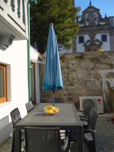 - une table avec un parapluie bleu et un bol de fruits dans l'établissement Casa da Barca, à Ponte da Barca