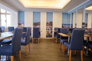 un restaurante con sillas azules, mesas y ventanas en Patria Hotel, en Lisboa