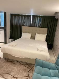 耶路撒冷的住宿－Lago Suites Hotel，卧室配有一张白色大床和一张蓝色椅子