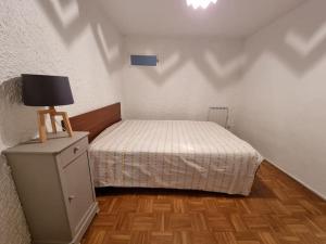 ein kleines Schlafzimmer mit einem Bett und einer Lampe auf einer Kommode in der Unterkunft Appartement paisible T1 de 38m2, Nantua in Nantua