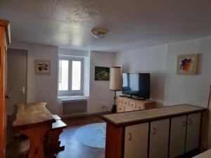 ein Wohnzimmer mit einem Flachbild-TV und einem Tisch in der Unterkunft Appartement paisible T1 de 38m2, Nantua in Nantua