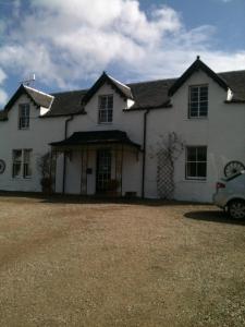 une maison blanche avec une voiture garée devant elle dans l'établissement Strathwhillan House, à Brodick