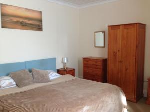 Strathwhillan House في بروديك: غرفة نوم بسرير وخزانة خشبية