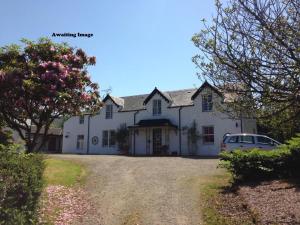 a white house with a car parked in the driveway at Strathwhillan House in Brodick