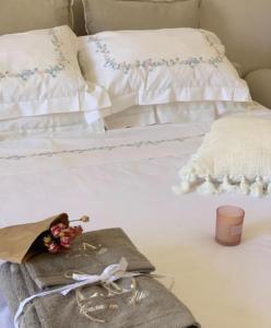 un letto bianco con una candela e fiori sopra di L.A. CASA IN ALTO a Tricase