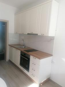 una cocina con armarios blancos y fregadero en Apartments and Rooms Tomas, en Podstrana