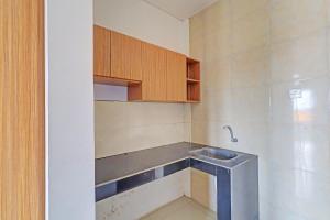 a small kitchen with a sink and wooden cabinets at OYO 92315 Prostay Bali in Denpasar