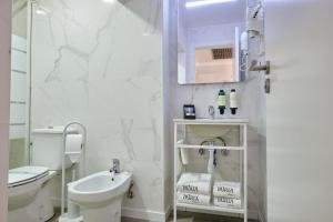 a white bathroom with a toilet and a sink at Patria Hotel in Lisbon