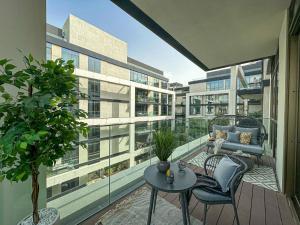 Cet appartement dispose d'un balcon avec une chaise et une table. dans l'établissement HiGuests - Charming Retreat in CityWalk With Balcony and Pool, à Dubaï