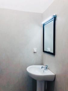 ein Bad mit einem Waschbecken und einem Wandspiegel in der Unterkunft Cannel view apartment Negombo in Negombo