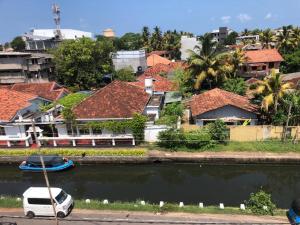 Cannel view apartment Negombo في نيجومبو: سيارة فان بيضاء متوقفة بجانب نهر به بيوت