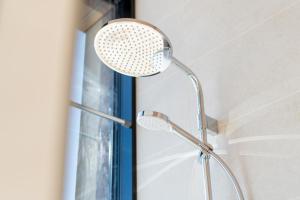 uma cabeça de chuveiro numa casa de banho ao lado de uma janela em Juniper Lux Minivilla Jacuzzi & Sauna 