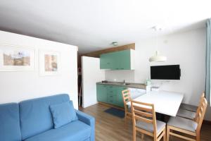 - un salon avec un canapé bleu et une table dans l'établissement Appartamenti Roulette Montana Marilleva 900, à Mezzana