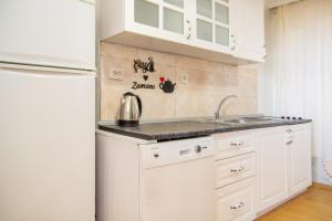 a white kitchen with a sink and a refrigerator at Lovely House with Sea View and Backyard in İzmir