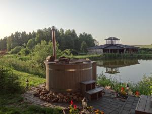 a bath tub sitting next to a body of water at Sodyba PILIAKIEMIS in Kurkliškės +19 photos