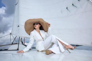 a woman in a white suit and hat sitting on a boat at Scarlet Pearl Cruises in Ha Long