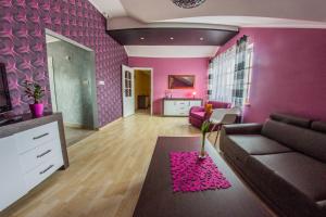 sala de estar con sofá y pared de color rosa en Apartamenty pod Zamkiem, en Łapalice