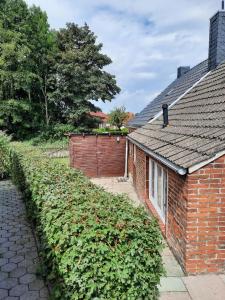 a brick house with a hedge next to a building at Ferienhus Aline in Krummhörn