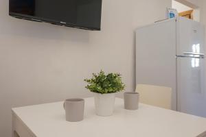 un mostrador blanco con dos plantas con un refrigerador en I Host Apartment - Fiuggi 59, en Milán