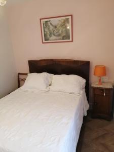 um quarto com uma cama com lençóis brancos e um candeeiro em Lanteuil Maison de vacances à côté de brive et collonge la rouge em Lanteuil