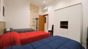 Un dormitorio con una cama roja y azul y un escritorio. en BILOCALE Porta Napoli, en Brindisi