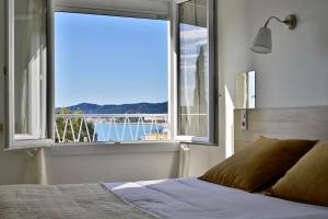 a bedroom with a window with a view of the ocean at Hôtel La Petite Bohème in Le Lavandou