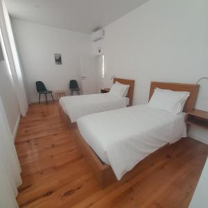 two twin beds in a room with wooden floors at DOURO B&B Avenida in Resende