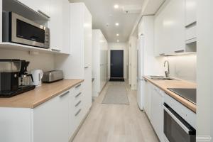 a kitchen with white cabinets and a hallway at Hilmantori Apartments by Hiekka Booking in Kalajoki