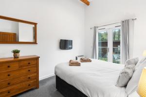 ein Schlafzimmer mit einem Bett, einer Kommode und einem Spiegel in der Unterkunft House 5 Ironcroft - Modern Pet-friendly, Walk to beach & village in Porthtowan