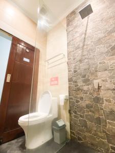a bathroom with a toilet and a stone wall at ROOM Ijen Dormitory & Tours in Banyuwangi