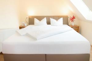 a bed with white sheets and pillows in a room at Hotel & Restaurant Waldblick in Pulsnitz