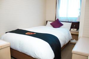 a bedroom with a white bed with a purple pillow at Grand Park Hotel Excel Kisarazu in Kisarazu