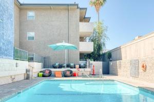 a swimming pool with an umbrella and chairs and a building at Pasadena 2BR w Gym Pool nr Colorado Ave LAX-863 in Pasadena