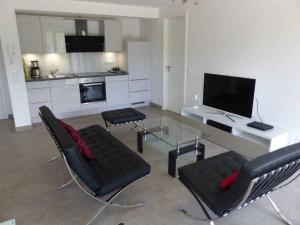 ein Wohnzimmer mit einem TV, einem Tisch und Stühlen in der Unterkunft Strandresidenz Appartement Haubentaucher G22 in Binz