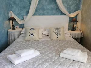 un letto con lenzuola e cuscini bianchi di La Serra Sul Mare a Monterosso al Mare