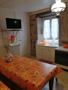 uma cozinha com uma mesa com um cobertor laranja em Lanteuil Maison de vacances à côté de brive et collonge la rouge em Lanteuil